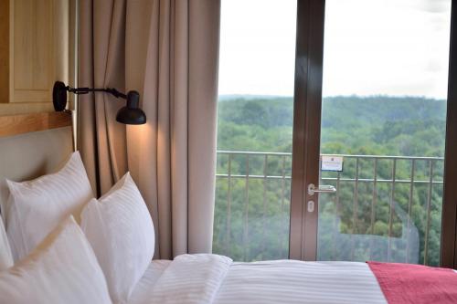 a bedroom with a bed and a large window at Famvida Hotel Lubuklinggau in Lubuklinggau