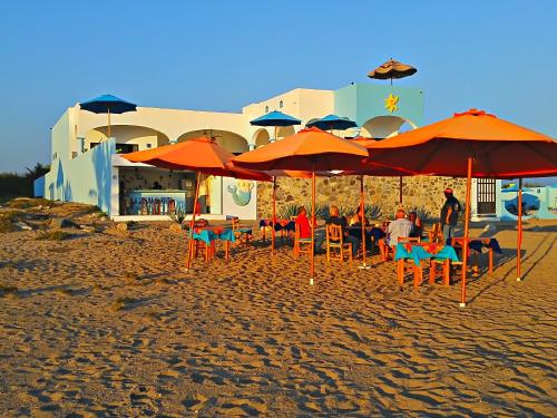 a group of people sitting under umbrellas on the beach at Villa Star of the Sea in Barra de Navidad