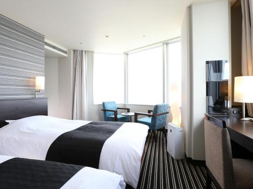 a hotel room with two beds and a desk at APA Hotel & Resort Tokyo Bay Makuhari in Chiba