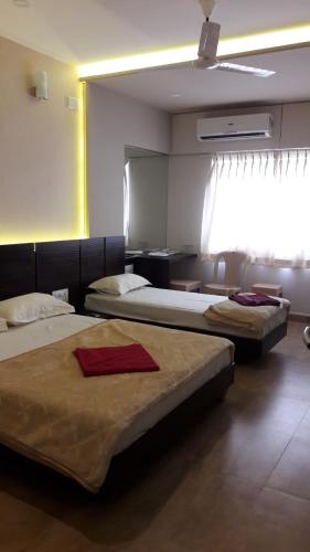 a room with two beds and a window with avertisement at Navaratna Palace in Belgaum