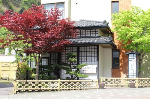 une maison avec un arbre rouge devant elle dans l'établissement Kashoutei Hanaya, à Noboribetsu