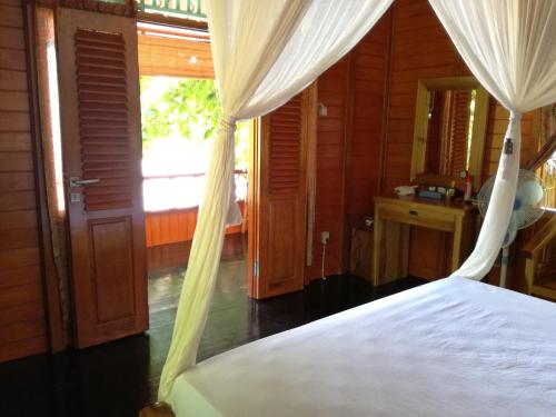 a bedroom with a bed with curtains and a window at Raja Laut Dive Resort Bunaken in Bunaken