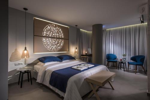 a bedroom with a large bed and blue chairs at Lavris City Suites in Heraklio Town