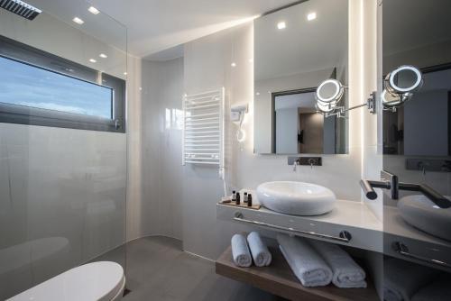 a white bathroom with a sink and a mirror at Lavris City Suites in Heraklio Town