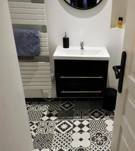 La salle de bains est pourvue d'un lavabo et de carrelage noir et blanc. dans l'établissement Magnifiques Appartements Hyper Centre, à Nantes
