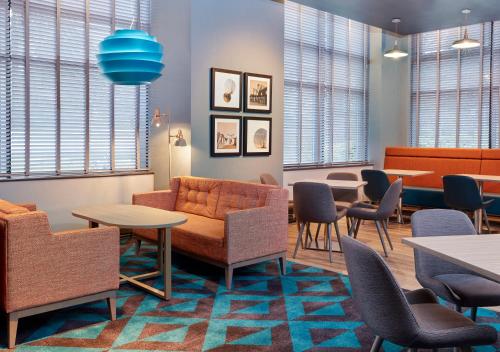 a waiting room with chairs and tables and windows at Leonardo Hotel Southampton in Southampton