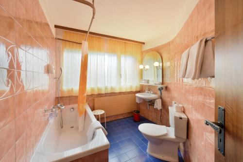 a bathroom with a tub and a toilet and a sink at Schlosshotel - Self Check-In Hotel in Brig