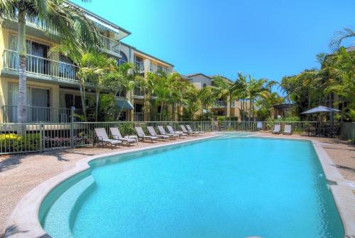 a swimming pool with lounge chairs and a building at Bila Vista Kirra Beachside Apartments in Gold Coast