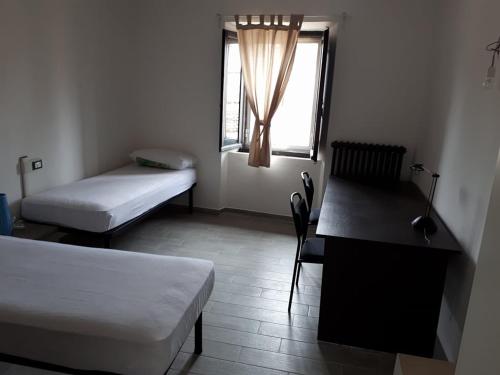 ウルビーノにあるPorta Maiaのベッド2台、デスク、窓が備わる客室です。