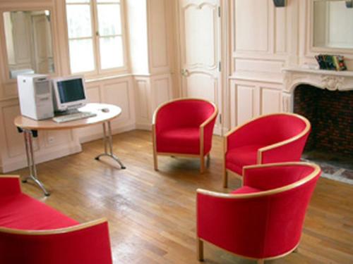a room with red chairs and a desk with a computer at Domaine de Surgy in Surgy