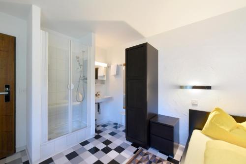 a bathroom with a shower and a black and white checkered floor at Schlosshotel - Self Check-In Hotel in Brig