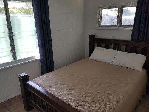 a bedroom with a wooden bed with two windows at Apurla Island Retreat in K'gari Island (Fraser Island)