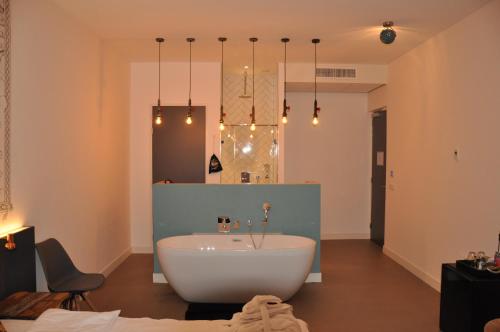 a bathroom with a white tub and a mirror at Hotel Rauw aan de Kade in IJmuiden