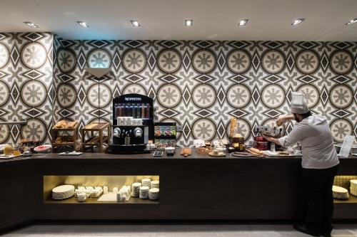 a chef preparing food at a counter in a restaurant at Catalonia Magdalenes in Barcelona