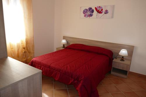 a bedroom with a red bed with a red blanket at Parco Meridiana in Scalea