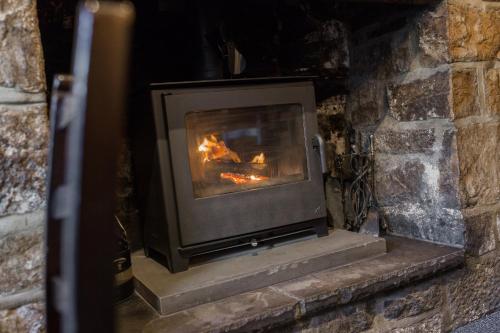 a stone fireplace with a fire in it at Black Horse Hotel in Grassington