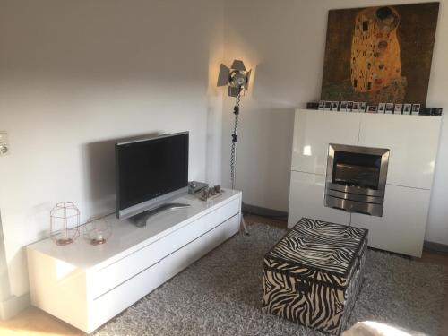 uma sala de estar com televisão numa parede branca em B&B 't Wehrzien em Selfkant