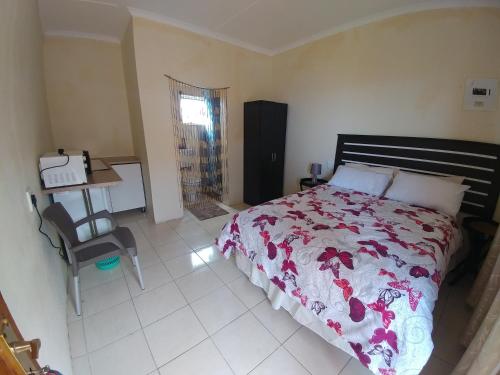 a bedroom with a bed and a desk and a chair at Hillside View Guesthouse in Coffee Bay