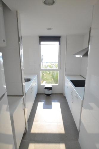 a white kitchen with a window and a toilet in it at Apartamentos Marina Suites in Grao de Castellón