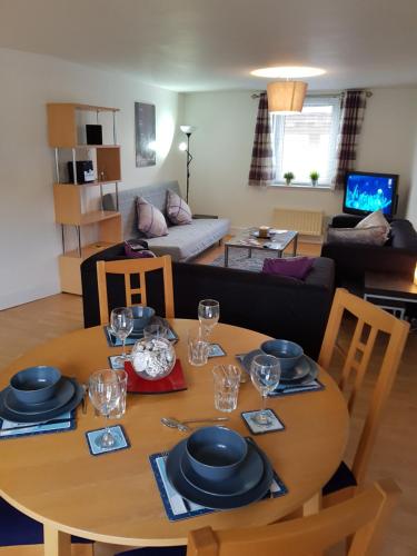 エディンバラにあるExecutive Open Plan Apartment, Leithのリビングルーム(木製テーブル、皿、グラス付)