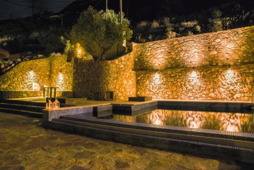 a stone wall with a pool at night at Evexia Villa in Thólos