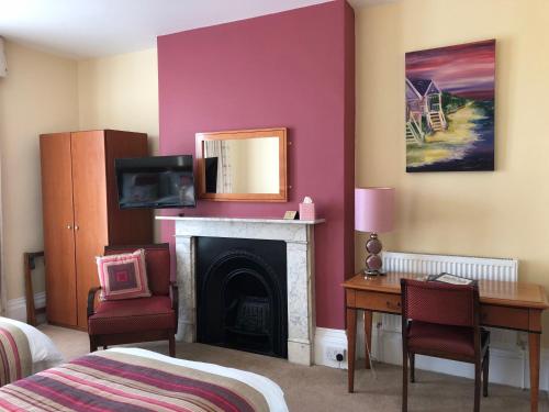 a bedroom with a fireplace and a bed and a desk at The Burleigh in Hunstanton