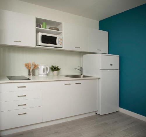 a white kitchen with a sink and a microwave at Diana Hotel in Haifa