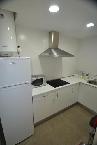 a white kitchen with a refrigerator and a sink at Apartamentos Marina Suites in Grao de Castellón