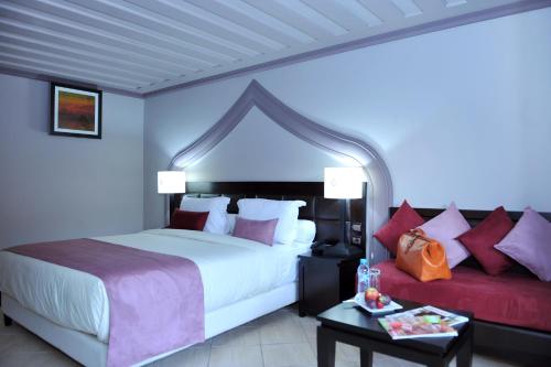 a bedroom with a large bed and a red couch at Blue Sea Le Printemps in Marrakesh