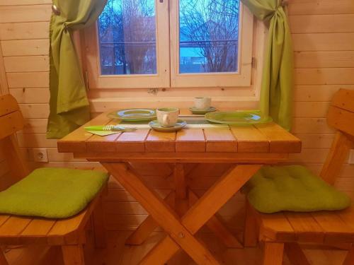 a wooden table with green cushioned chairs and a window at Brvnara Borovik in Cetinje