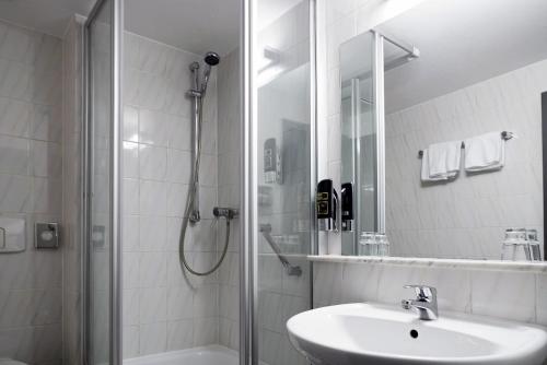 a white bathroom with a sink and a shower at Colour Hotel in Frankfurt/Main