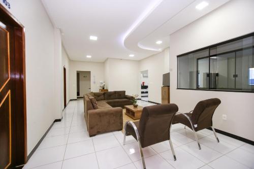 uma sala de estar com um sofá, uma mesa e cadeiras em O Neves Hotel em Guanambi