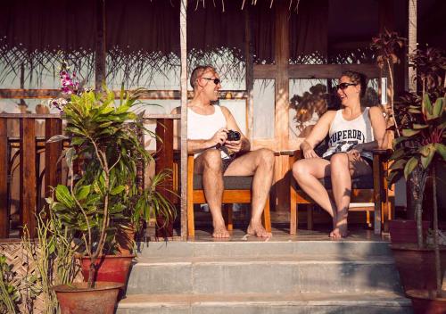 two men sitting in chairs on a porch at Mariposa Beach Grove in Agonda