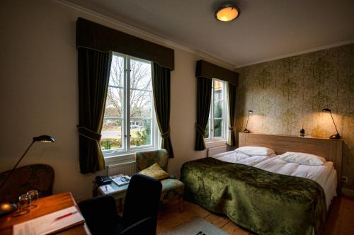 a bedroom with a bed and two windows at Gimo Herrgård in Gimo