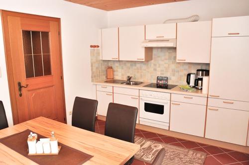 シャルニッツにあるFerienwohnung Veraのキッチン(白いキャビネット、テーブル、椅子付)