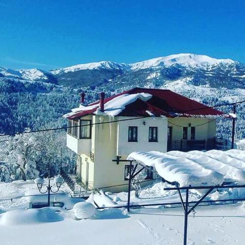a house covered in snow with mountains in the background at Natasa Rooms in Filippaioi