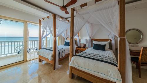 two beds in a bedroom with a balcony at Hemingways Watamu in Watamu