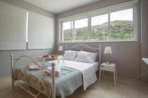 a bedroom with a bed and two windows and a table at Angel-kolymvari4you in Kolymvari