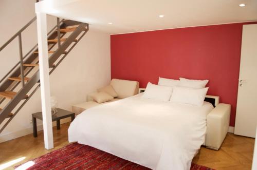 une chambre avec un lit blanc et un mur rouge dans l'établissement AzurAppart Elegant Studio Centre, à Nice