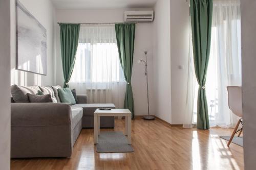 a living room with a gray couch and green curtains at Apartment Ada in Belgrade