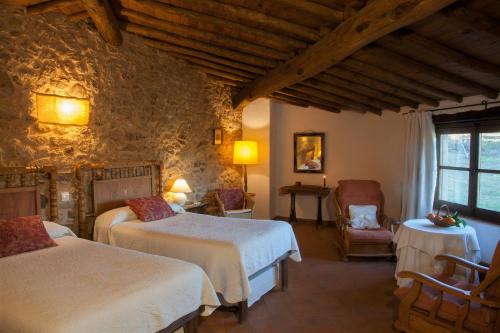 una habitación de hotel con 2 camas y una silla en Casa Rural El Cabezo, en San Martín de Trevejo