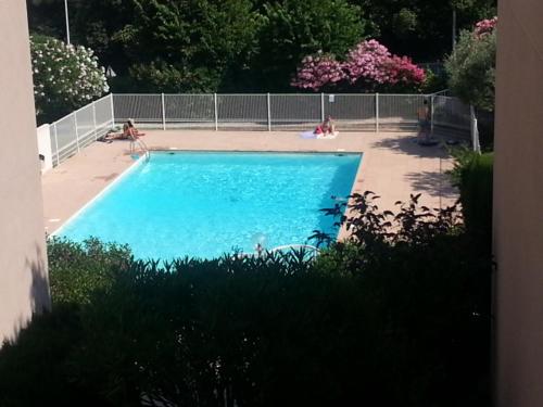 une grande piscine bleue avec des personnes assises autour de celle-ci dans l'établissement Park Fabron 2 Pieces Terrasse Piscine Parking, à Nice
