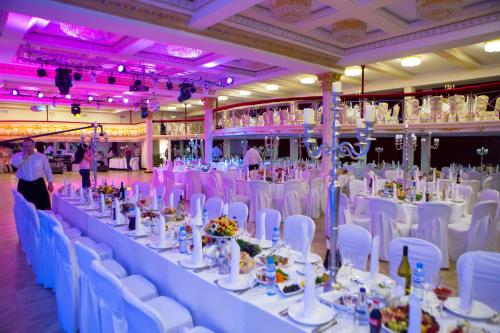 un salón de banquetes con mesas blancas y sillas blancas en Salut New Moscow Hotel, en Vnukovo