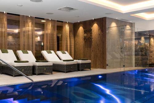 um átrio do hotel com uma piscina e cadeiras em AlpenParks Hotel & Apartment Taxacher em Kirchberg in Tirol