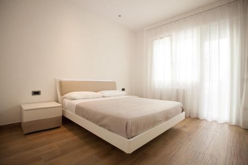 a white bedroom with a white bed and a window at Residence Torino in Chioggia