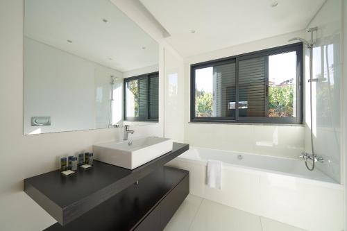 La salle de bains blanche est pourvue d'un lavabo, d'une baignoire et d'une fenêtre. dans l'établissement Funchal View Apartments, à Funchal