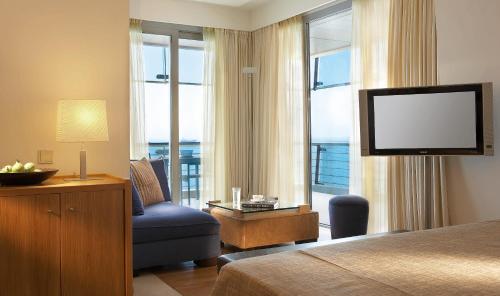 a hotel room with a tv and a bed and a chair at Daios Luxury Living in Thessaloniki