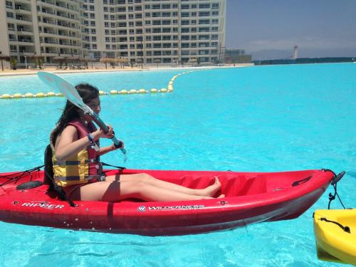 une femme assise dans un kayak rouge dans l'eau dans l'établissement Departamento Resort Laguna del Mar, à La Serena