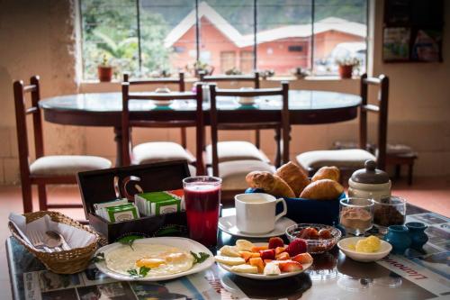 einen Tisch mit Frühstücksspeise darauf mit einem Tisch im Hintergrund in der Unterkunft Hosteria Llanovientos in Baños