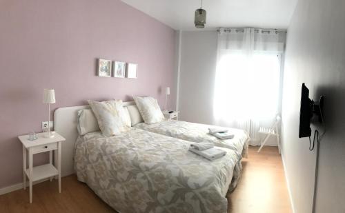 a white bedroom with a bed and a window at Alojamientos Olga in Pamplona